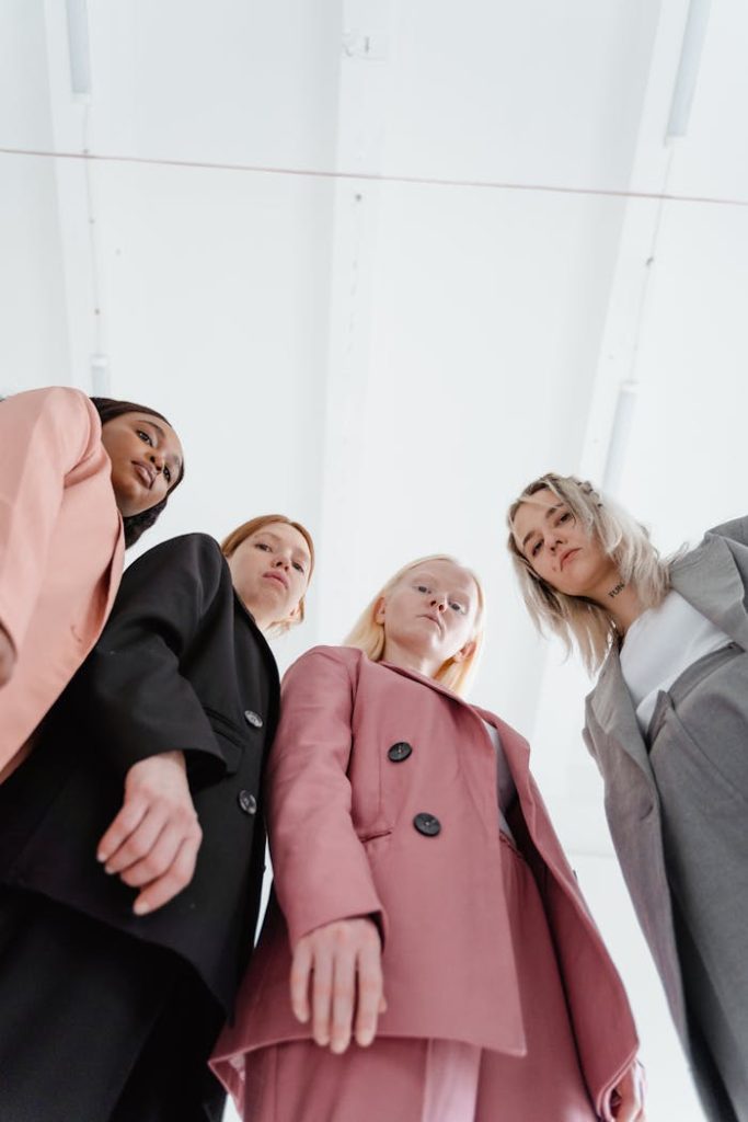 Four diverse women in business suits shot from a low perspective on a white background.