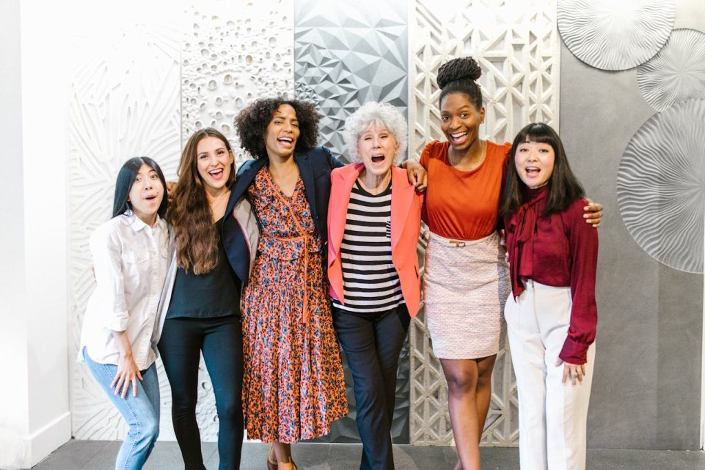 Group of diverse women happily posing together in a stylish, modern office space.