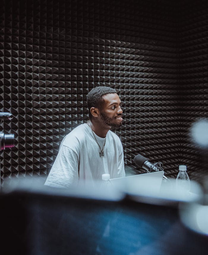 African American man podcasting in a soundproof studio with microphone and laptop.